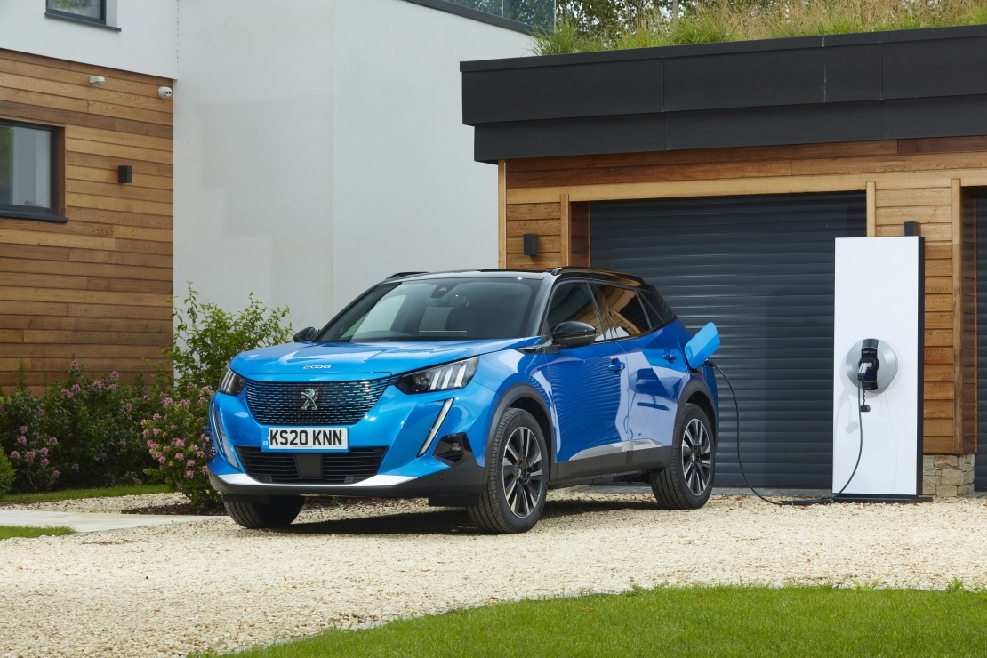 Peugeot e-2008 in blue parked outside home garage charging 
